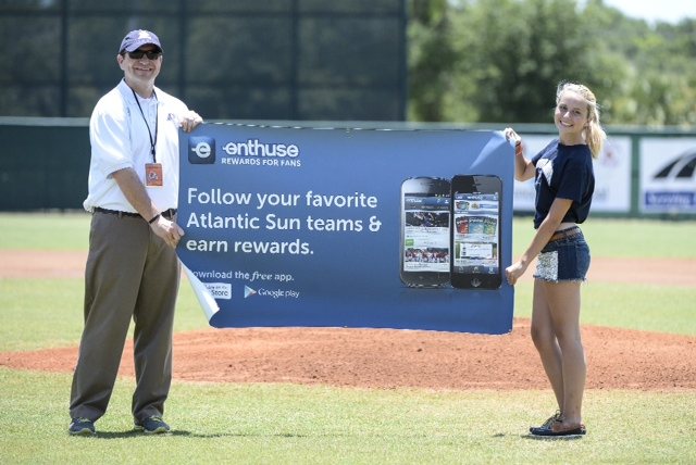Championship staff and the First Pitch winner holding an Enthuse banner on the field